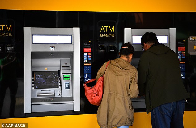 Fake bank notes are circulating in Australia's capital cities at an alarming rate as the simple way to spot a counterfeit note is revealed (pictured, people use an ATM in Adelaide)