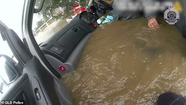 Police attempt to get the elderly driver out of the van's cab as floodwaters rapidly rise around them