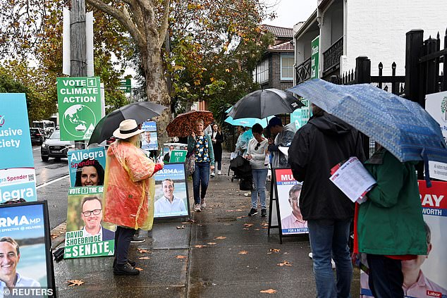 Pictured: Voters line up outside in the rain at the Waverley suburb polling station to cast their ballots on the day of the national election in Sydney