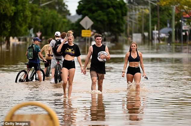 Local residents walk through floodwater on March 31, 2022 in Lismore, Australia