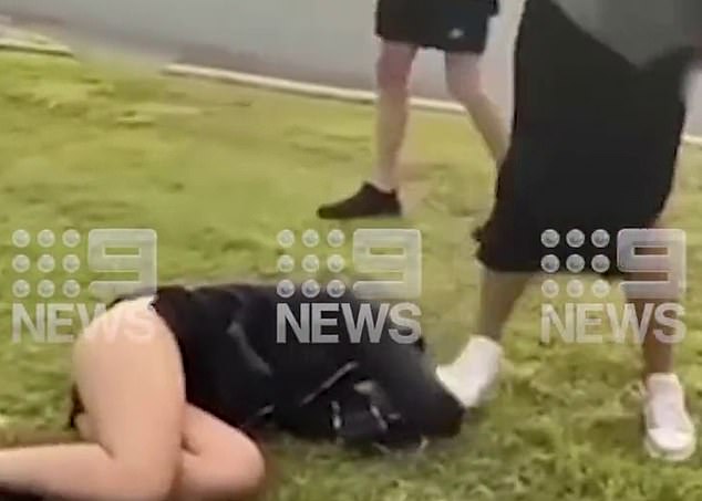 The defenceless victim (pictured, lying on the ground) eventually gets to her feet after being kicked, punched and stomped on by two girls